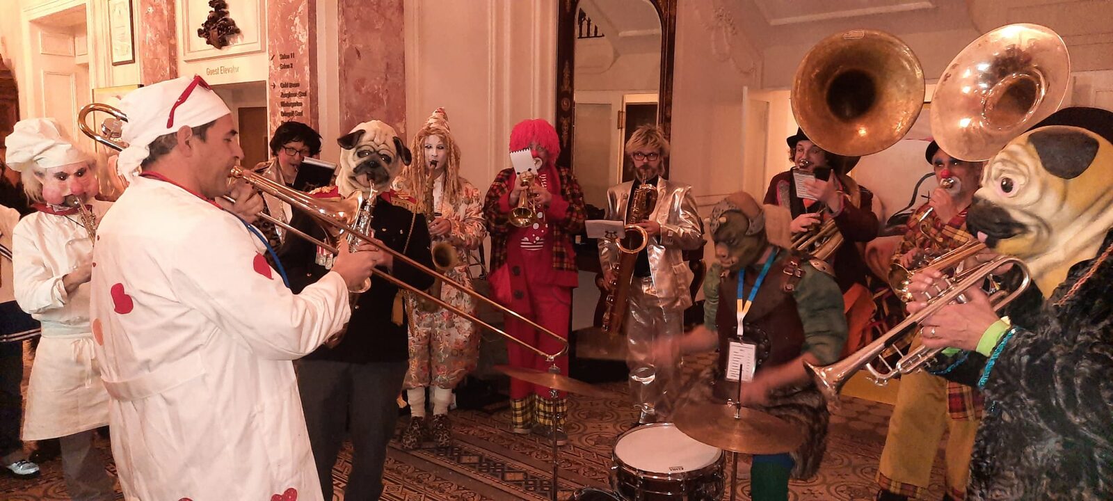 Sujet 2022: Alte Sujets — die Band spielt in einer bunten Mischung früherer Kostüme, von Koch über Mops bis Clown